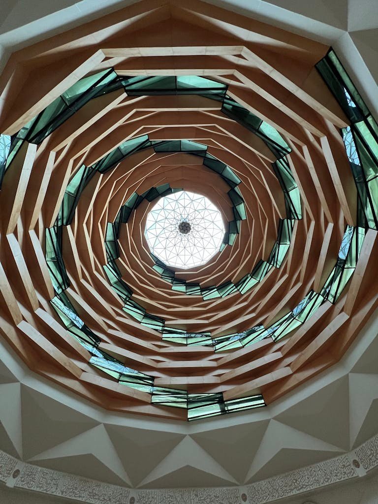 Stunning upward view of a geometric spiral ceiling, showcasing intricate architectural design.